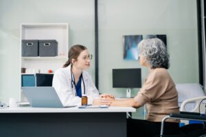Female doctor speaking to elderly woman sitting at a desk