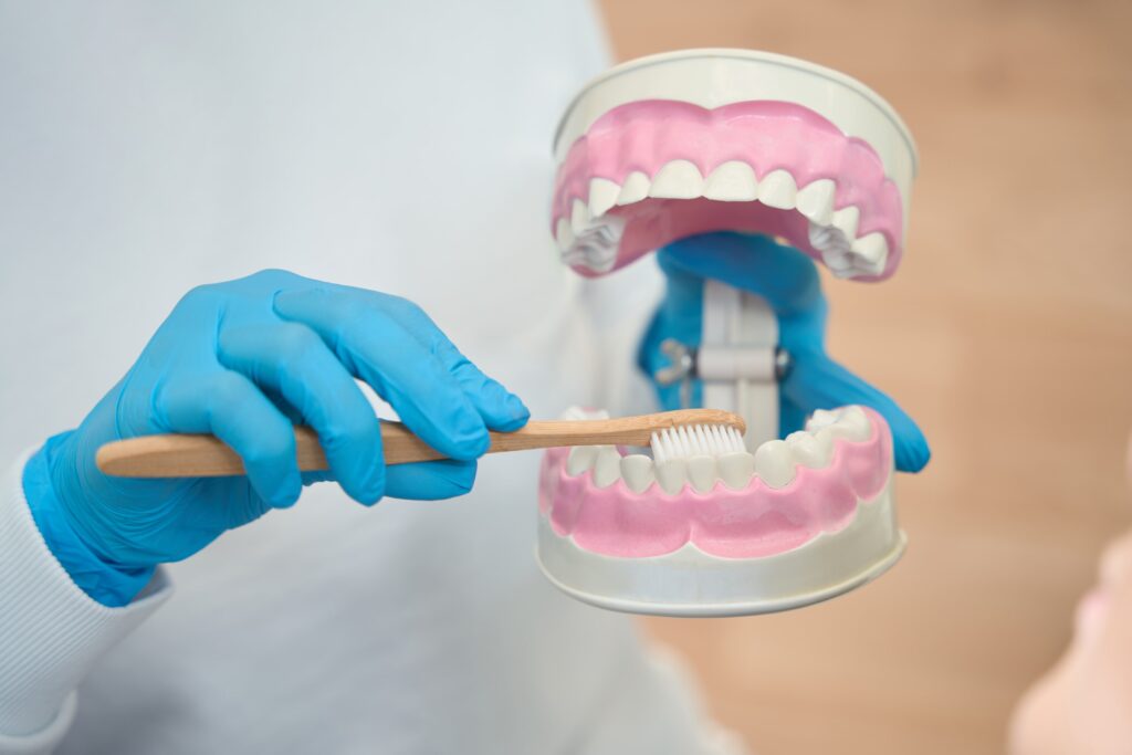 a oral surgeon demonstrating how to properly brush your teeth to prevent cavities